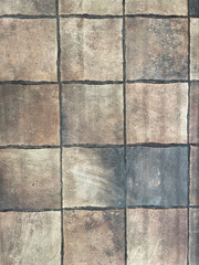 Fototapeta premium Weathered stone tile floor texture with square ceramic tiles and dark grout lines. Neutral earthy tones create a rustic, vintage background suitable for interior design, architecture, surface patterns