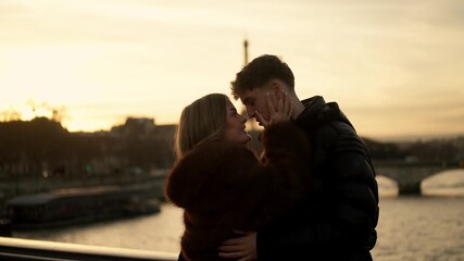 A loving couple embraces in Paris France with the Eiffel Tower visible in the background during a golden sunset The scene captures a moment of romance and affection in a popular travel destination.