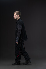Male model in oversized techno-style outfit, studio portrait on neutral gray