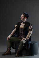 Theatrical representation of wealthy medieval nobleman in ornate brocade costume featuring cape and...