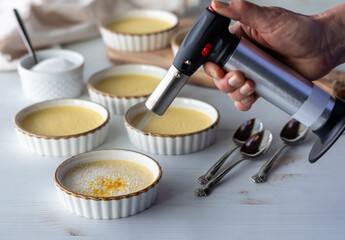 Preparing Creme Brulee dessert ramekins with a torch for browning the sugar.