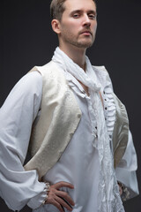 A young man in an early Baroque outfit, a white blouse with lace and ruffles, a white vest, a classic vintage suit, an unbuttoned vest, an image with a touch of decadence, a theatrical hero, a photo