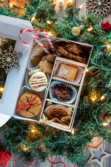 Baked treats in a DIY festive cookie box surrounded by lights and greenery.