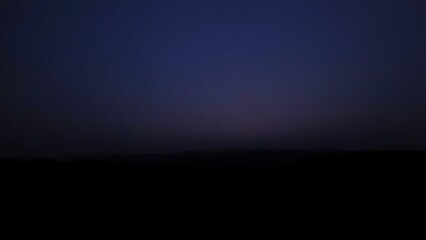 anticipatory. A vast landscape at dawn with a deep indigo sky and silhouetted trees. travel magazines, destination branding, designed for outdoor magazines and nature guides, used by SEO specialists.