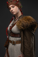 Female Viking warrior in fantasy costume with battle axe, photographed on gray, close-up