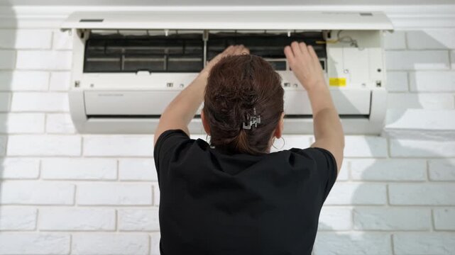 Service female install conditioner filters. A view of female hands takes the filters from the device, and install the filters for better working in apartment