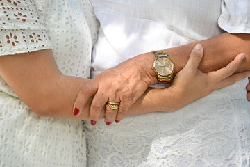 close up of woman arms with gold watch and ring, mother and daughter hugging in sunny garden, elegant feminine accessories and jewelry, connection and affection concept in outdoor setting