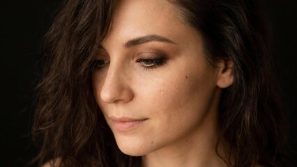 Close-up portrait of a thoughtful young woman with dark hair looking down.