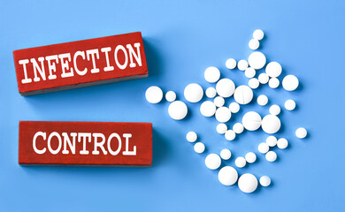 INFECTION CONTROL - words on wooden red bars on a blue background with pills