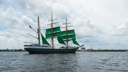 Three-masted sailing vessel moving across open water © jia