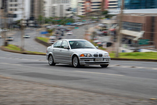 Silver BMW 3 Series E46 sedan front view panning shot, Classic German car driving in city