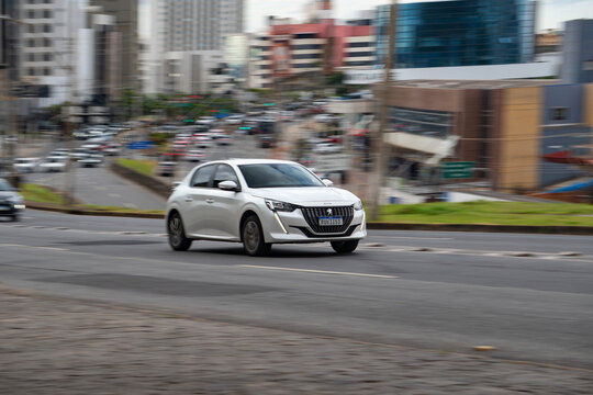 White Peugeot 208 hatchback front view panning shot, French compact car driving in city