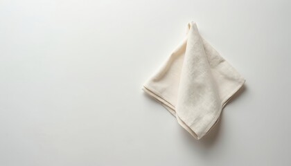 Plain undyed linen napkin folded neatly into square rests on white background. Soft textured fabric object displays clean lines, subtle folds, suitable for minimalist table settings eco friendly