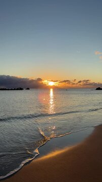 Peaceful morning at the beach with glowing sun on the horizon and gentle waves