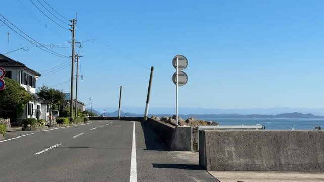 POV walking along a scenic coastal road with a view of the blue sea and distant islands
