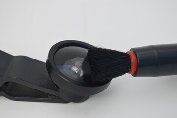 Professional cleaning of a mobile phone camera lens using a specialized black soft brush