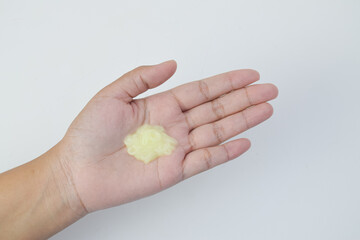 Close up of yellow cosmetic gel or lotion on a human palm, isolated on white background