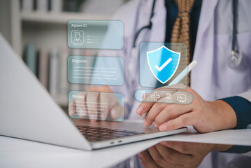 Doctor working on laptop with digital patient ID record interface and security shield. Medical healthcare data analysis, insurance protection, and electronic diagnosis technology concept.