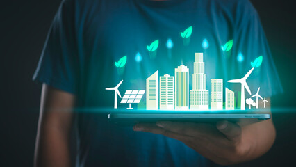 Man holding tablet with green eco city hologram. Sustainable energy, ESG environment concept, solar and wind power technology for future smart urban life.