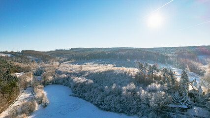Obraz premium Winterpanorama mit schneebedeckten Hügeln, Wald und klarer Sicht