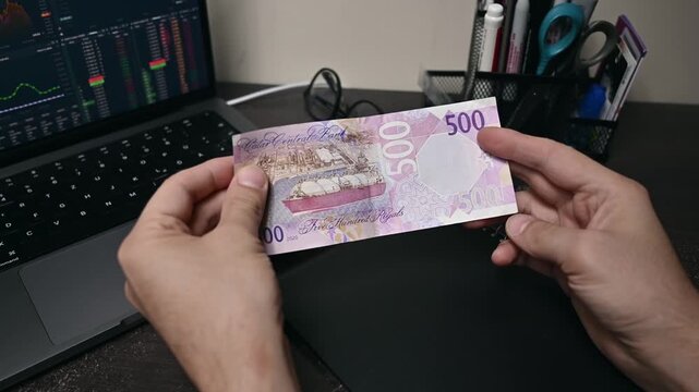 Businessmen check genue Qatar money bills on hand, which is called Riyal. Paper banknotes of various denominations