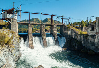 Hydro power plant near a river amidst mountains under a clear blue sky during daytime