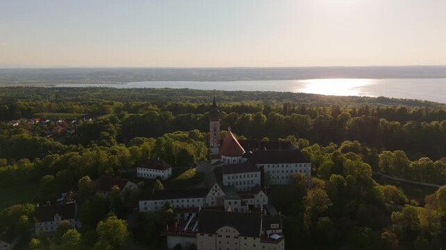 Drone footage of Kloster Andechs on Holy Mountain in Upper Bavaria, Germany. View of monastery, baroque church, lake Ammersee and green countryside near Munich at golden hour. Luftbild Heilige Berg. 