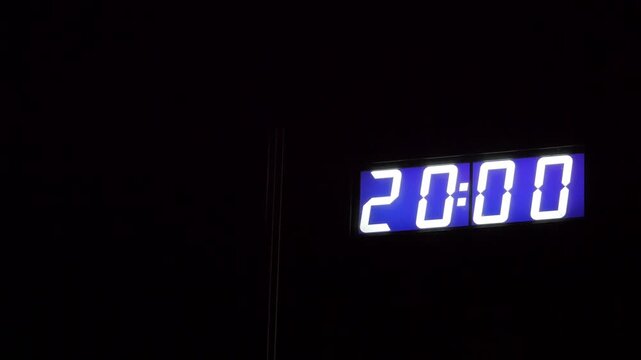 Purple digital clock showing 20 00 on black background