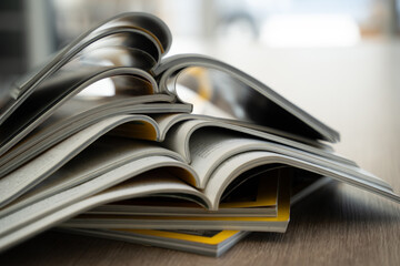 Close up of stacked open magazines showing curved pages and blurred background. Publishing, journalism and printed media concept with room for text.