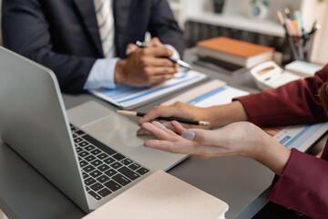 A collaborative startup meeting showing professionals reviewing financial charts and discussing strategic ideas in a modern office setting.