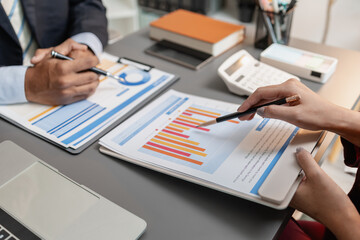 A business meeting scene where professionals review financial charts and exchange insights, highlighting strategic planning and collaborative decision making in a modern office environment.