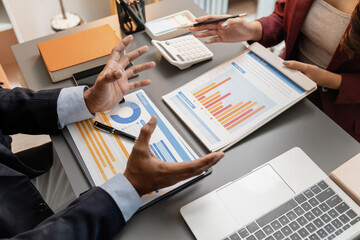 A business meeting scene where professionals review financial charts and exchange insights, highlighting strategic planning and collaborative decision making in a modern office environment.