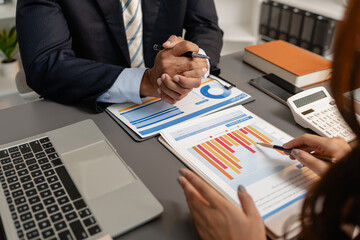A business meeting scene where professionals review financial charts and exchange insights, highlighting strategic planning and collaborative decision making in a modern office environment.