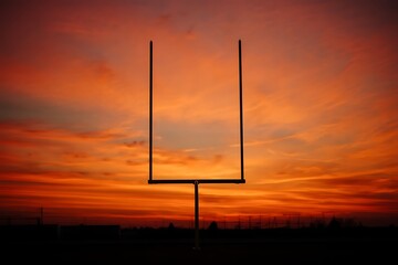 American football goalpost silhouetted against vibrant sunset sky