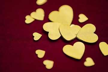 Obraz premium Golden hearts scattered on red velvet background