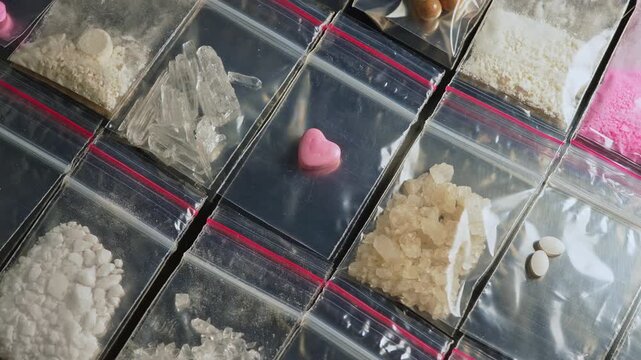 Pink heart shaped pressed pill ecstasy MDMA display, along with Fentanyl type opioid drugs in small packages, this drugs causing the most severe crisis in the world. Synthetic opioids Nitazenes.