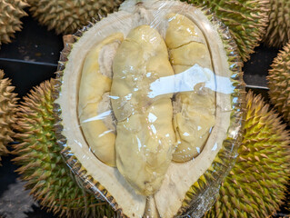 Ripe and fresh durian fruit is cut open, revealing the soft, yellow flesh