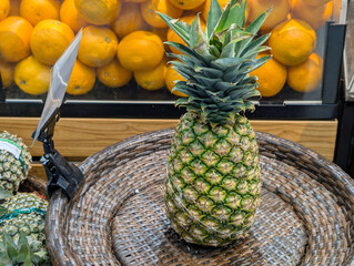 A whole ripe pineapple with bright colors is displayed on a simple woven basket.