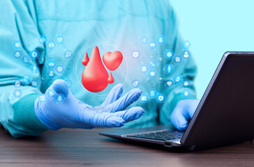 Doctor analyzes blood donation statistics on laptop. Concept of hospital logistics, transfusion management, and digital hematology. Doctor displays blood drop and heart icons.