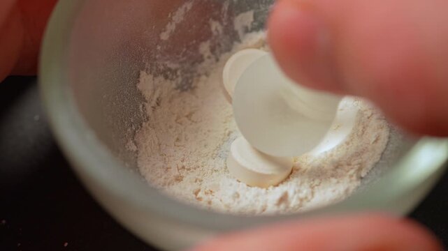 Drug dealer crushing prescription opioid drug to mix with fentanyl. Synthetic opioids and fentanyl crisis. On the streets it is injected, snorted sniffed, smoked, taken orally by pill or tablet.