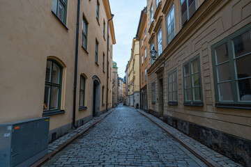 Obraz premium Narrow cobblestone street lined with historic buildings in Gamla Stan, Stockholm, Sweden.