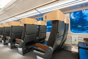 Empty modern train seats with wide windows and soft lighting, showing snowy scenery passing outside with motion blur, creating a calm winter travel atmosphere inside a clean passenger cabin.