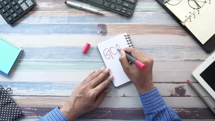 4k overhead view of hands writing goals on notebook with red marker, office desk with calculator and keyboard, planning and motivation