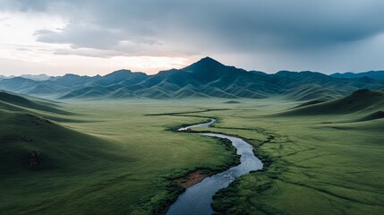Aerial view of a winding river flowing through a lush green valley with distant mountain peaks
