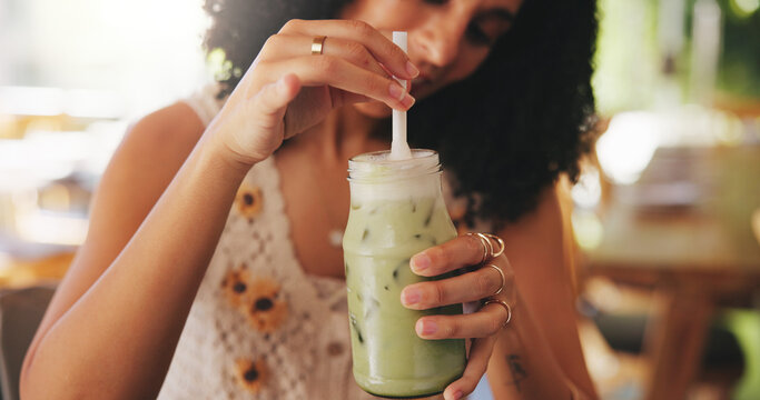 Hands, matcha or drink with woman in coffee shop with iced beverage for thirst, refreshing or hydration with stir. Green smoothie, milkshake and person mixing cold liquid in glass with straw at cafe