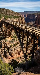 Massive wooden trestle bridge spans deep desert canyon under clear blue sky