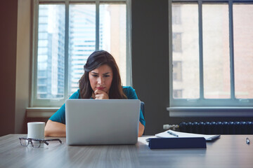 Woman, laptop and reading in office with idea, problem solving and editing in property listing. Estate agent, computer and thinking in business for project management, email feedback and review