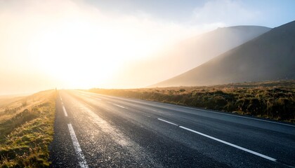 A serene road stretches towards a bright horizon, framed by misty mountains and soft sunlight