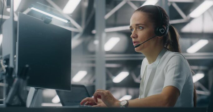 Female Operator Providing Remote Technical Assistance While Speaking on Headset in Setting Modern Enterprise Control Center. Concept of Customer Service, Troubleshooting, and Enterprise Support.