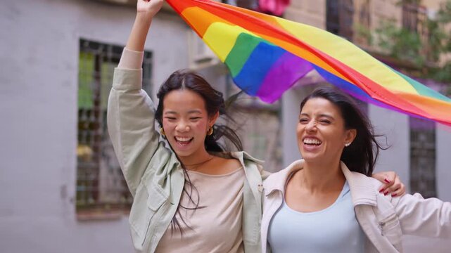 Lesbian couple celebrating pride and holding a rainbow flag